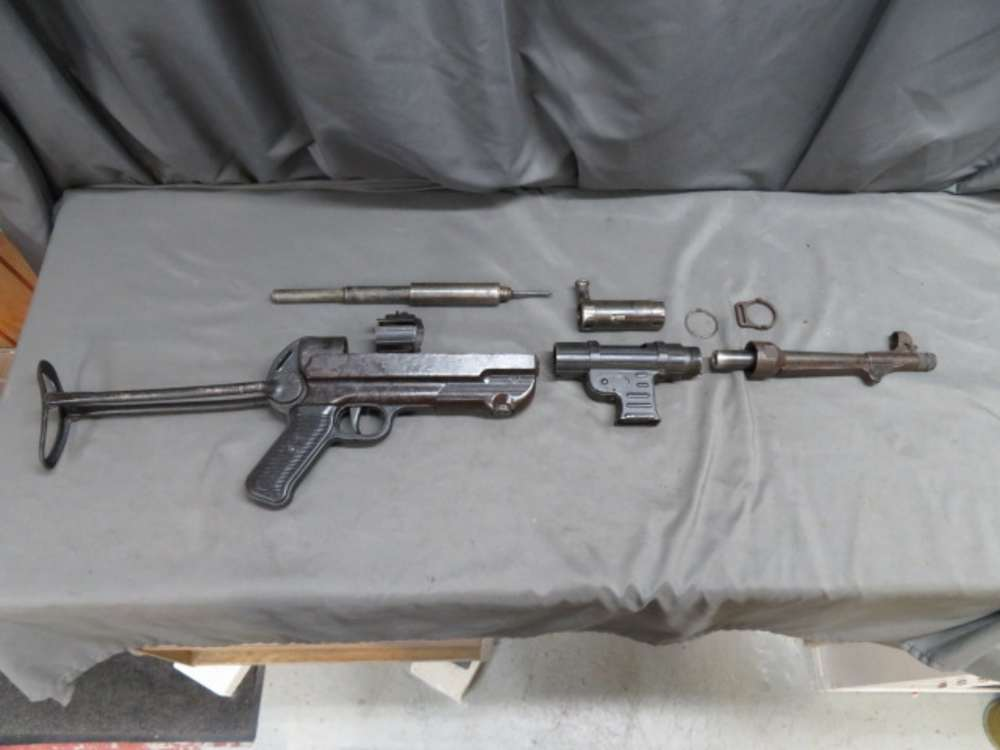 Full spread of a genuine WWII German MP 40 parts kit, showing receiver, barrel, bolt, and small components laid out on a table